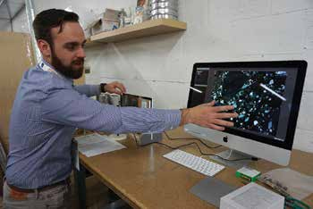 George Reo, WJE, applies a polarizing filter to a petrographic sample to view aggregate color